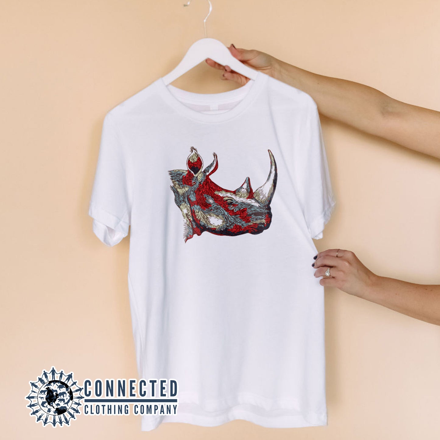 Hands Holding Hanger With  White Vanishing Into Extinction Rhino Tshirt - sweetsherriloudesigns - Ethically and Sustainable Clothing - 10% of proceeds are donated to rhino conservation