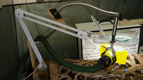 SnakeClamp flexible gooseneck arm and 3-finger clamp supporting dust collector vacuum in a workshop