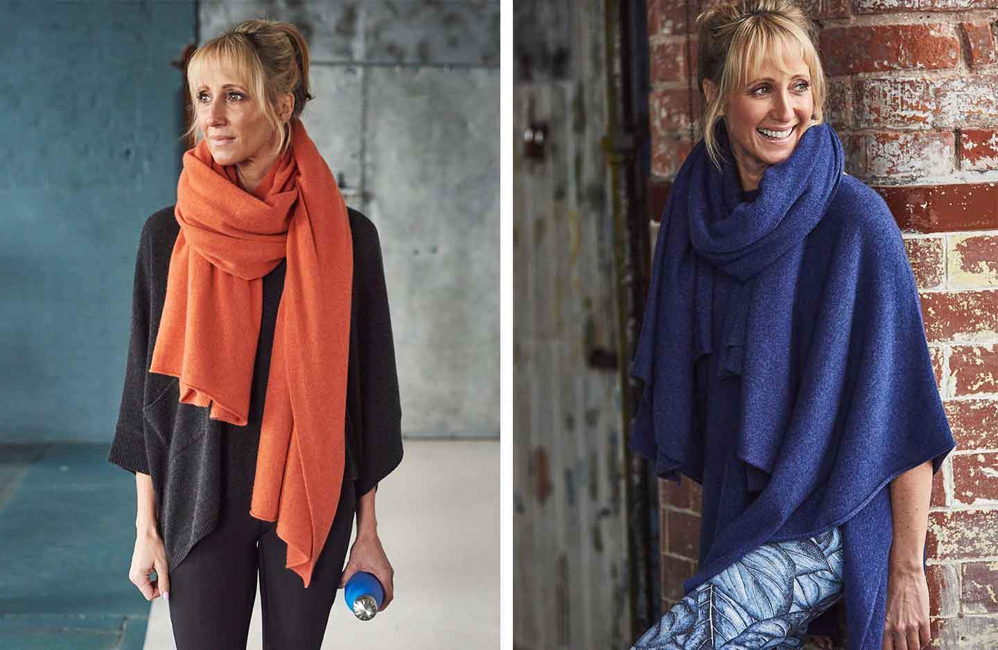 Women against brick wall in grey oversized cashmere poncho with orange cashmere scarf and women in blue cashmere poncho with blue cashmere scarf wrapped around neck