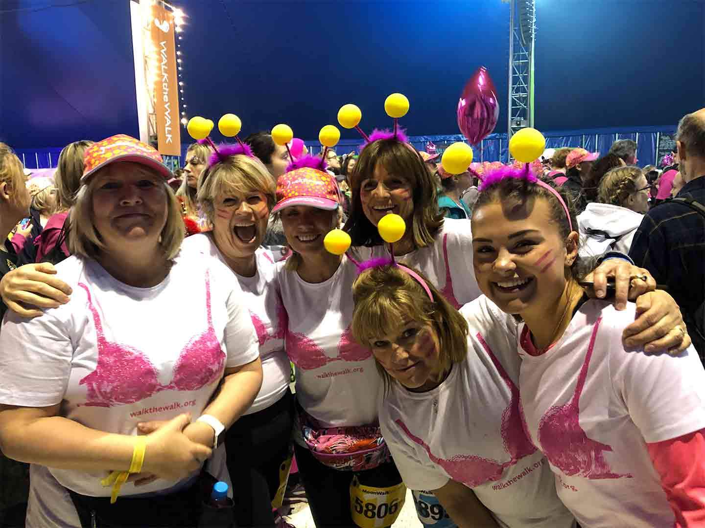 a-group-of-women-standing-together-in-white-t-shirts-with-pink-bras-waiting-to-start-the-Moon-Walk-2019