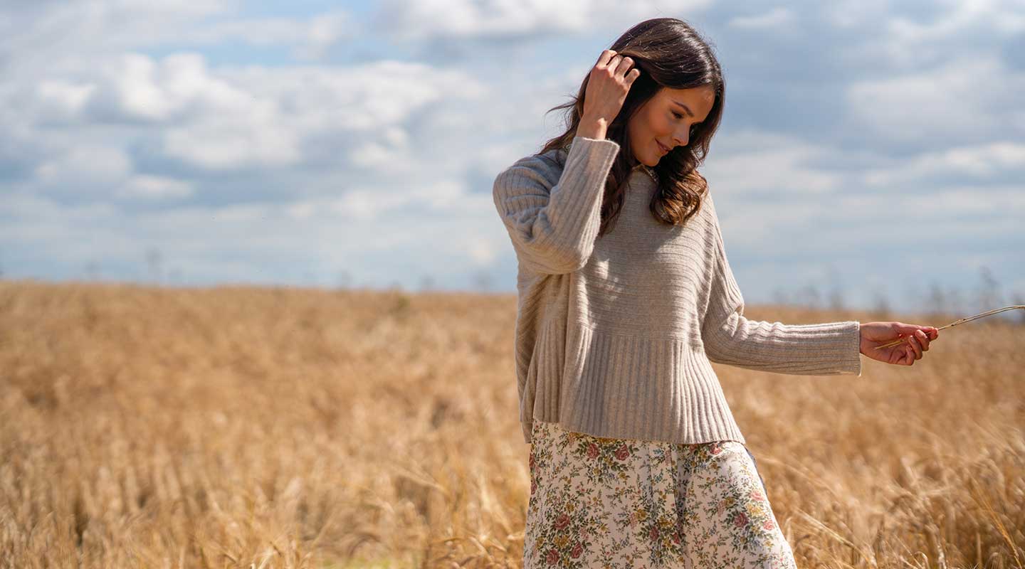 model in wheat field wearing neutral cashmere jumper