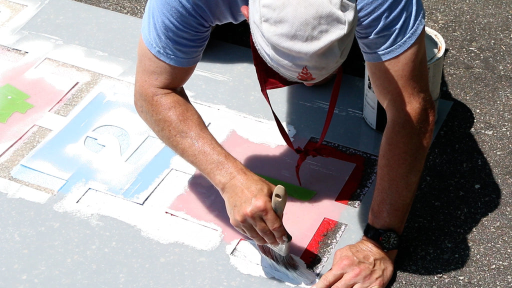 Use a brush to paint pavement paint through the stencil