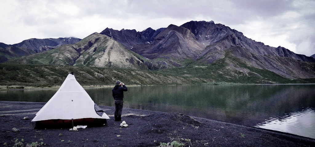 Backpacker stands outside ultralight tent shelter