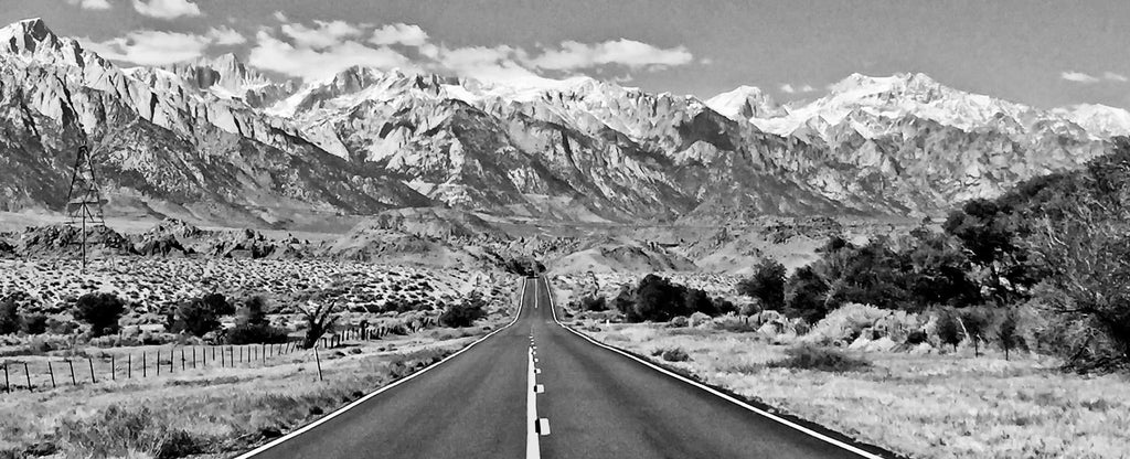black and white image of road leading to mountains