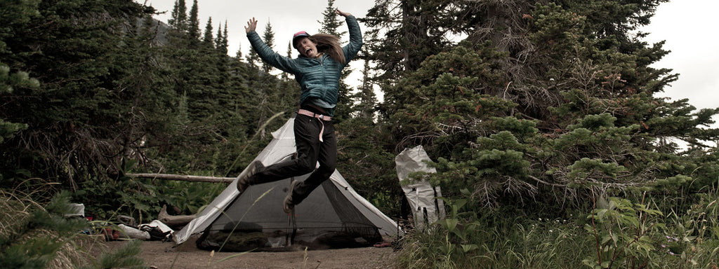 Ultralight backpacker poses in front of tent