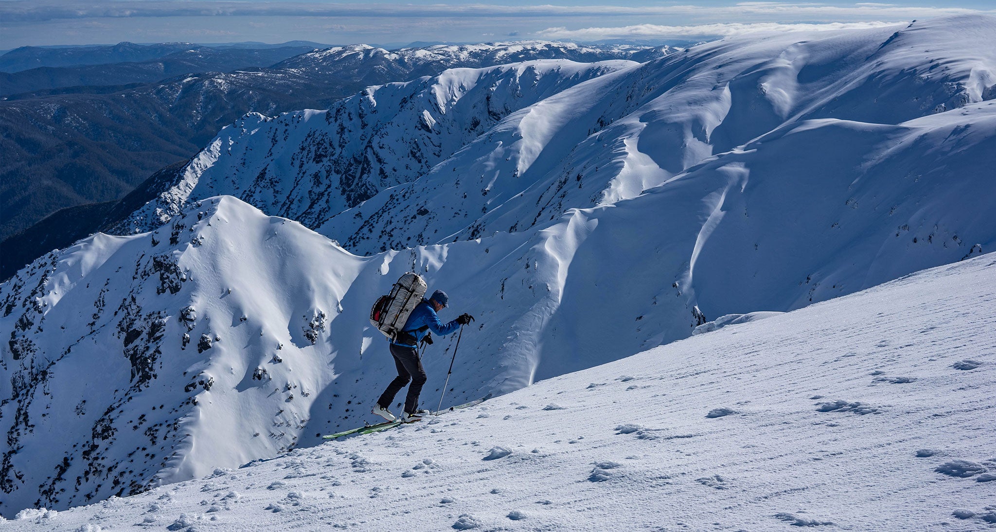 Backcountry skiier hikes along snowy peak