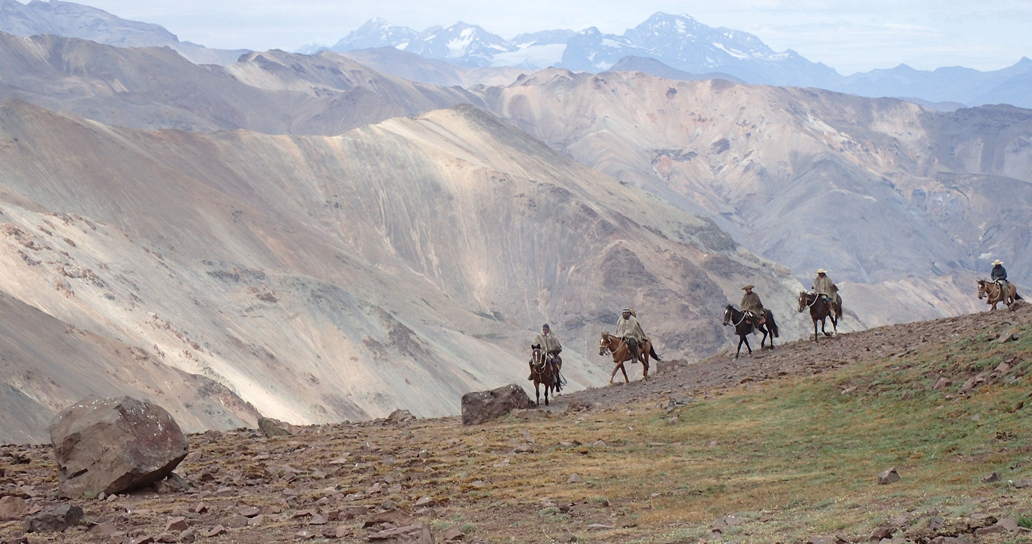 Men riding horses through the Mountains in Chile