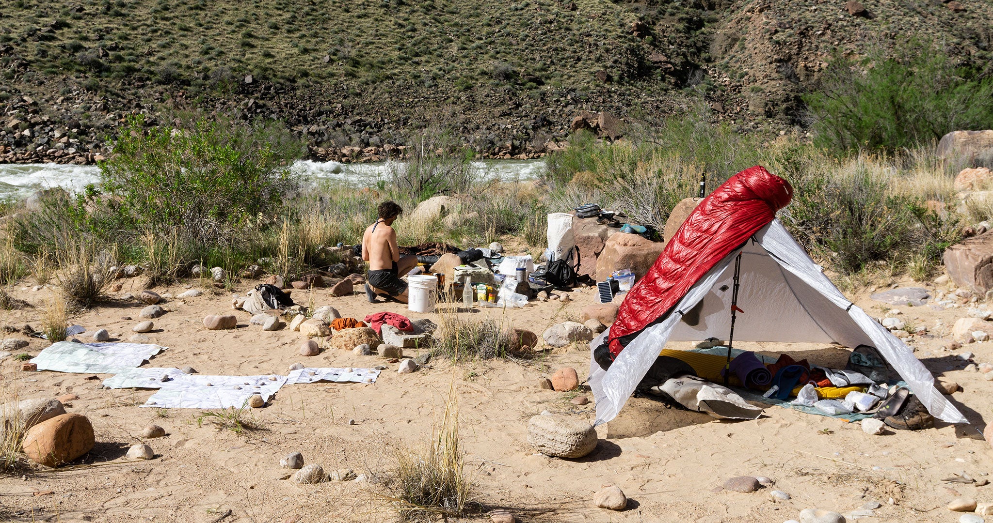 Ultralight Backpacker setting up camp along a river