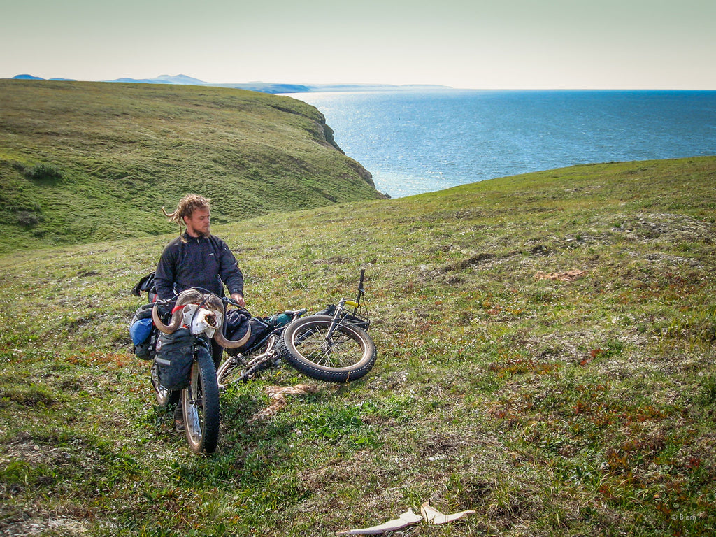 Bjørn poses with a musk ox skull, atop a sea cliff overlooking the Bering Sea on the Seward Peninsula