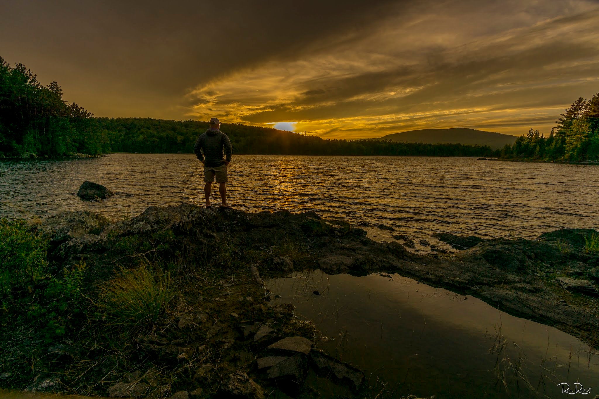 Man looks over a lake at sunrise