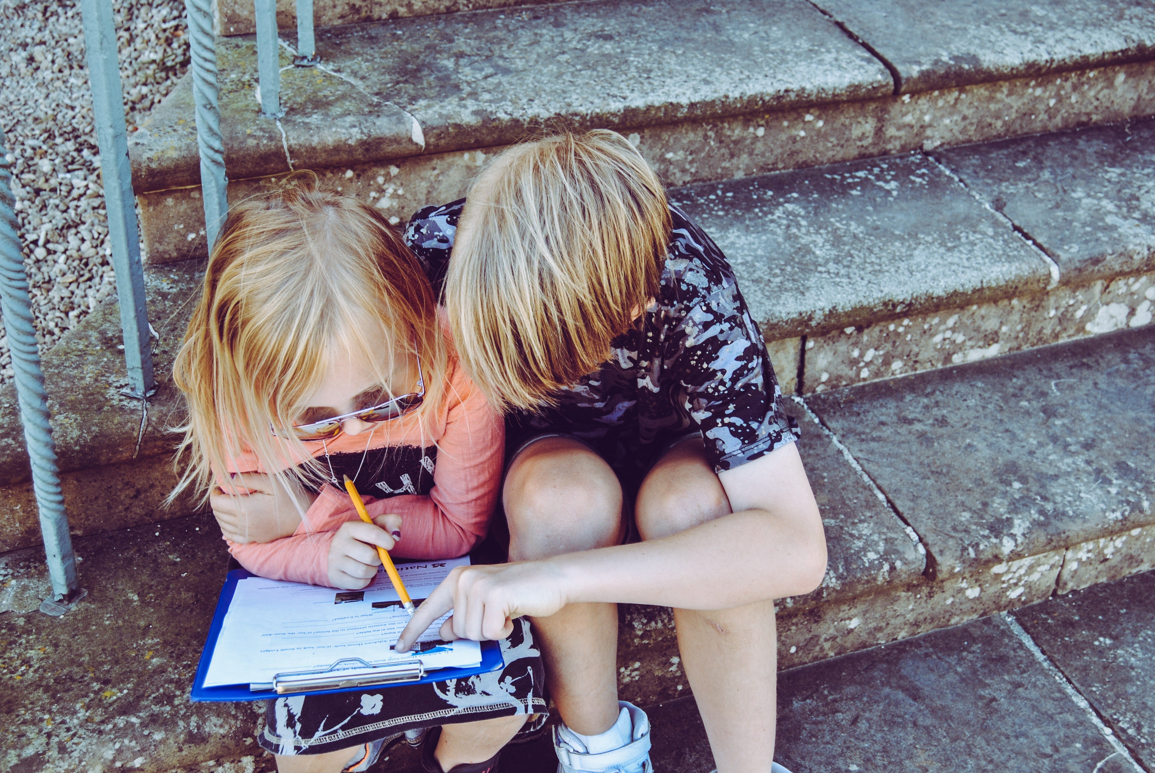 Older Sibling Helping With Homework on the Steps Outside of School