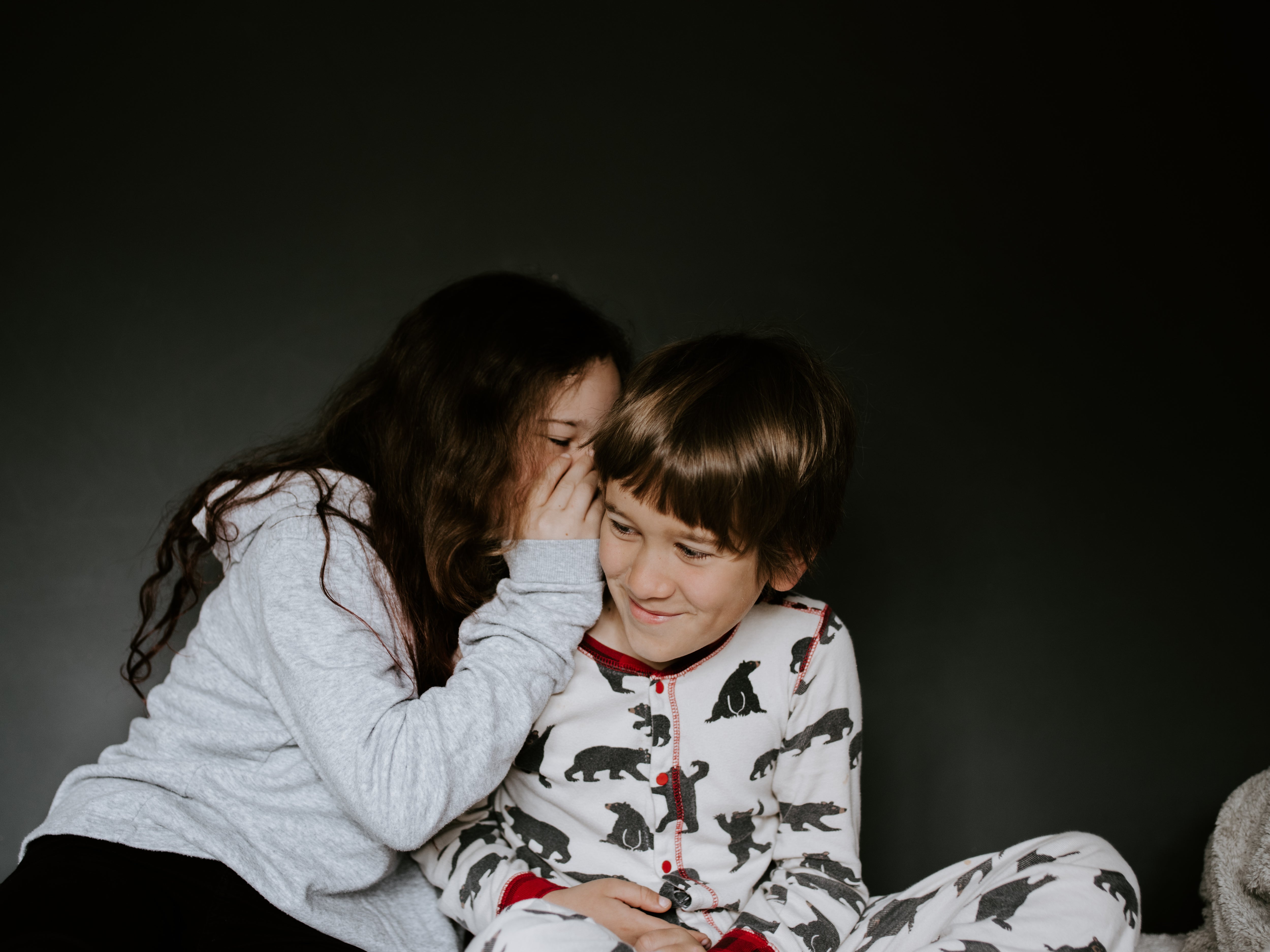 Older Sister Sharing Secret with Little Brother in Pyjamas