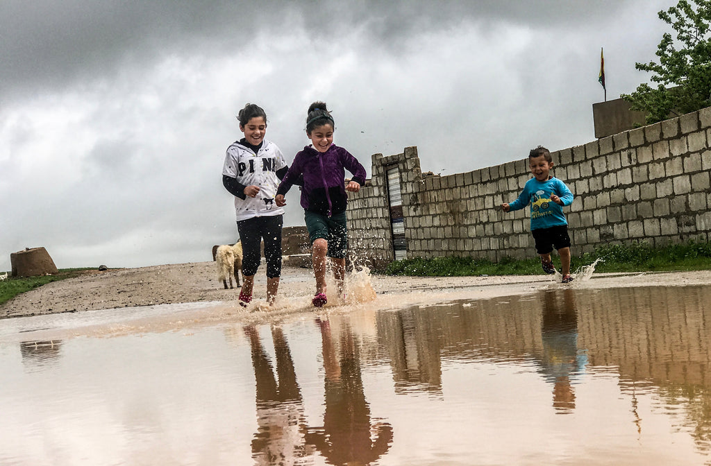 Kids playing at a beach running through a puddle