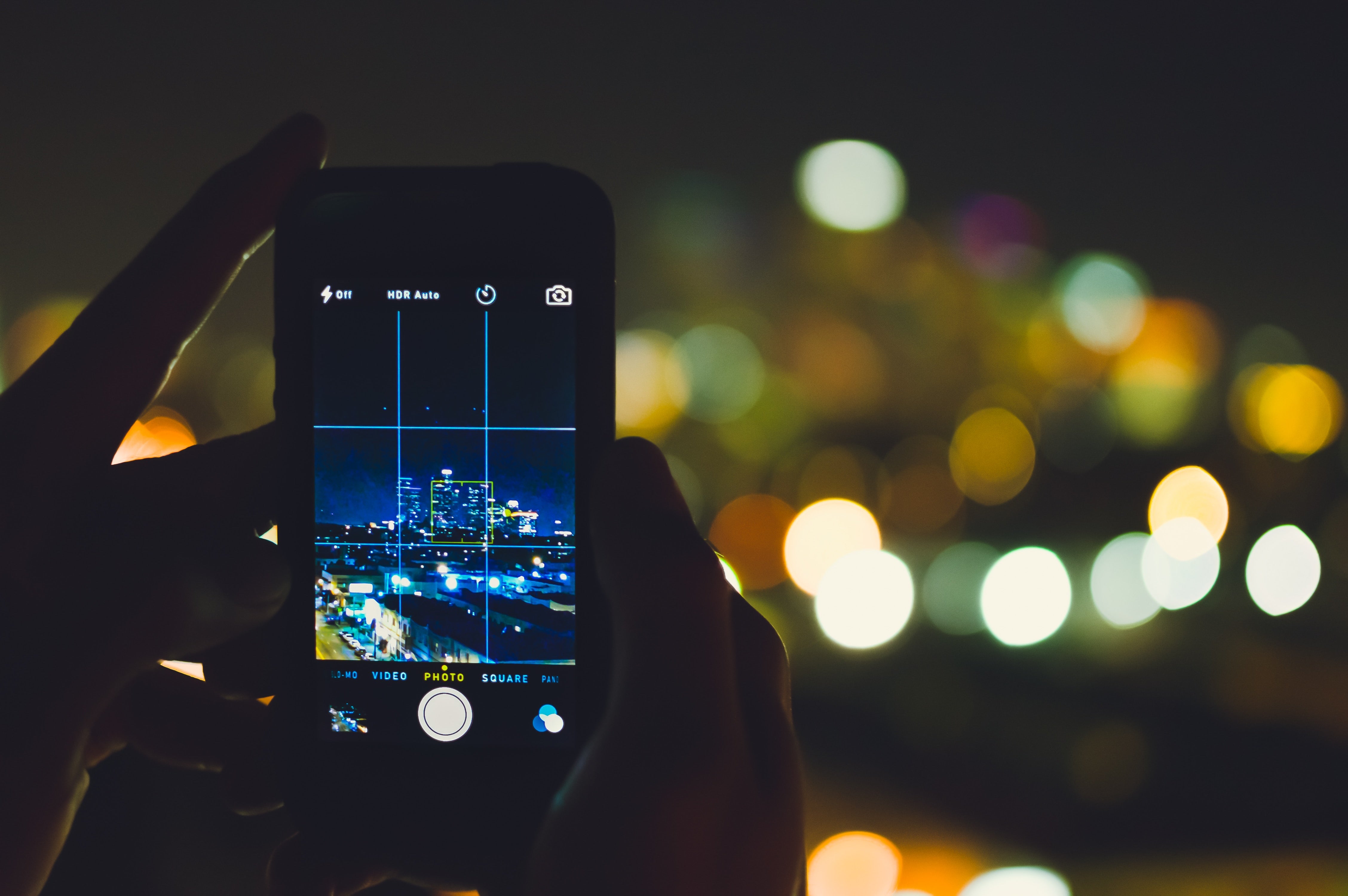 Person Capturing Photo of Nighttime Cityscape