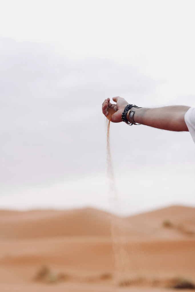 Sand falling through a person's hand at the beach