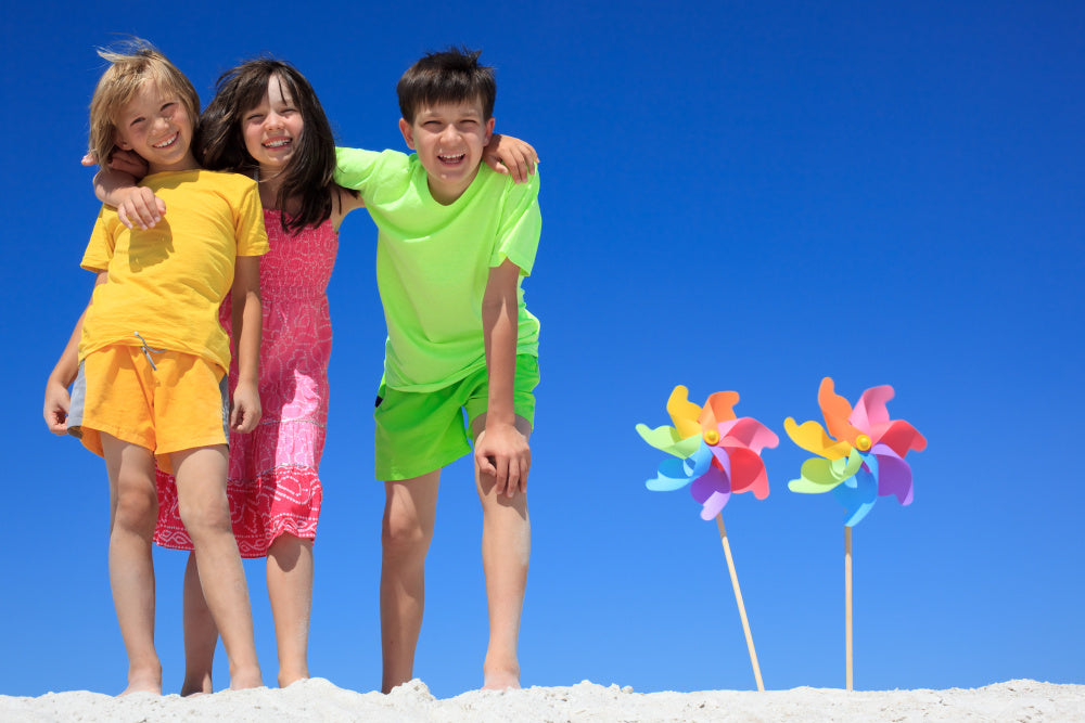 Kids on the beach with windmills in the sand