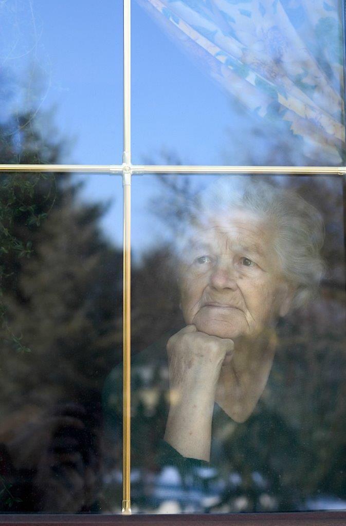 Elderly woman thoughtfully looking out a window