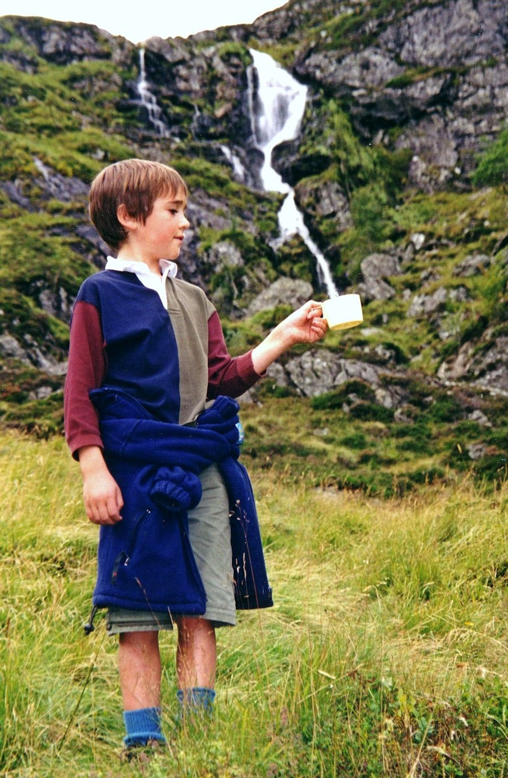 Forced perspective photo of a boy holding a cup with a waterfall pouring into it