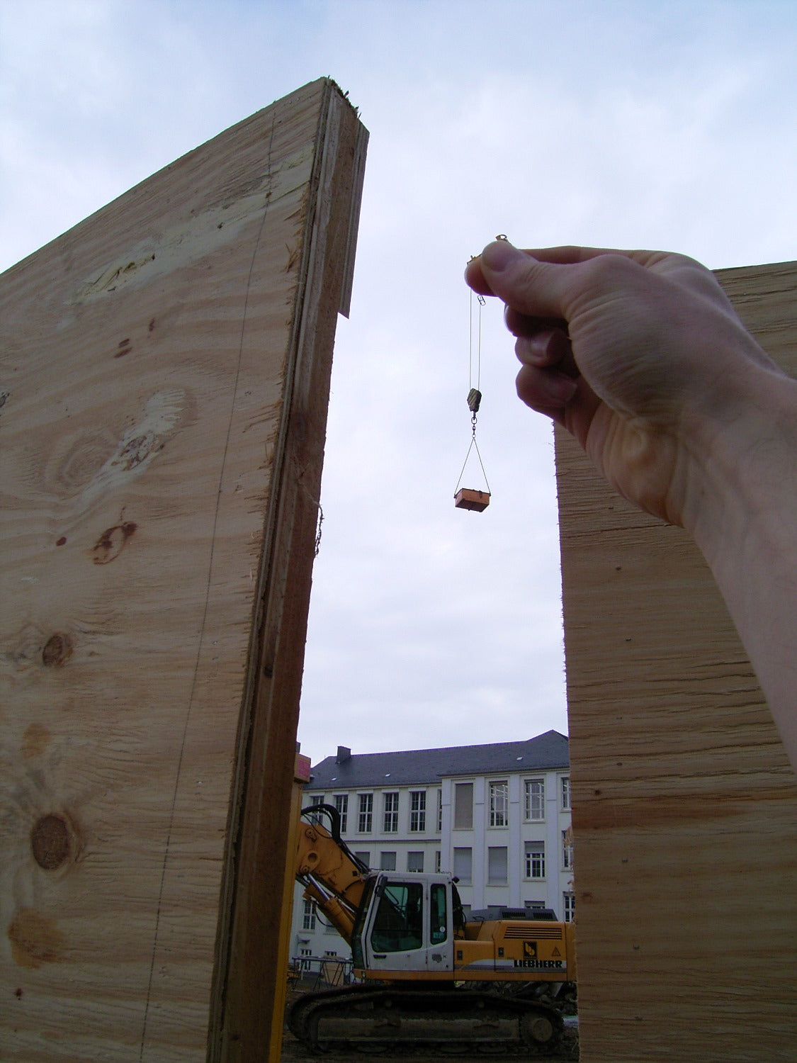 Forced perspective photo of a man holding onto a crane's load