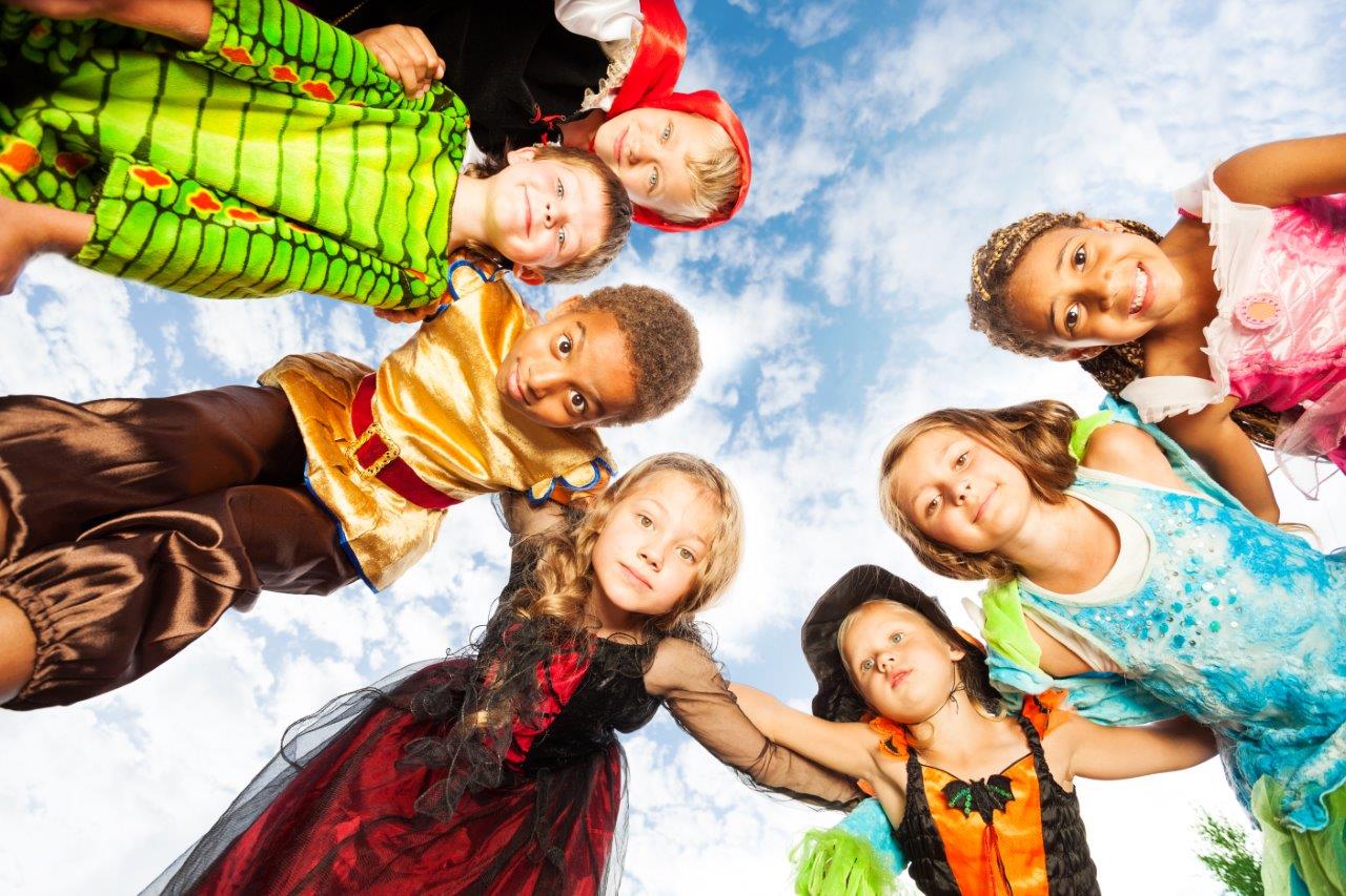 Group photo of kids in Halloween costumes looking down at the camera