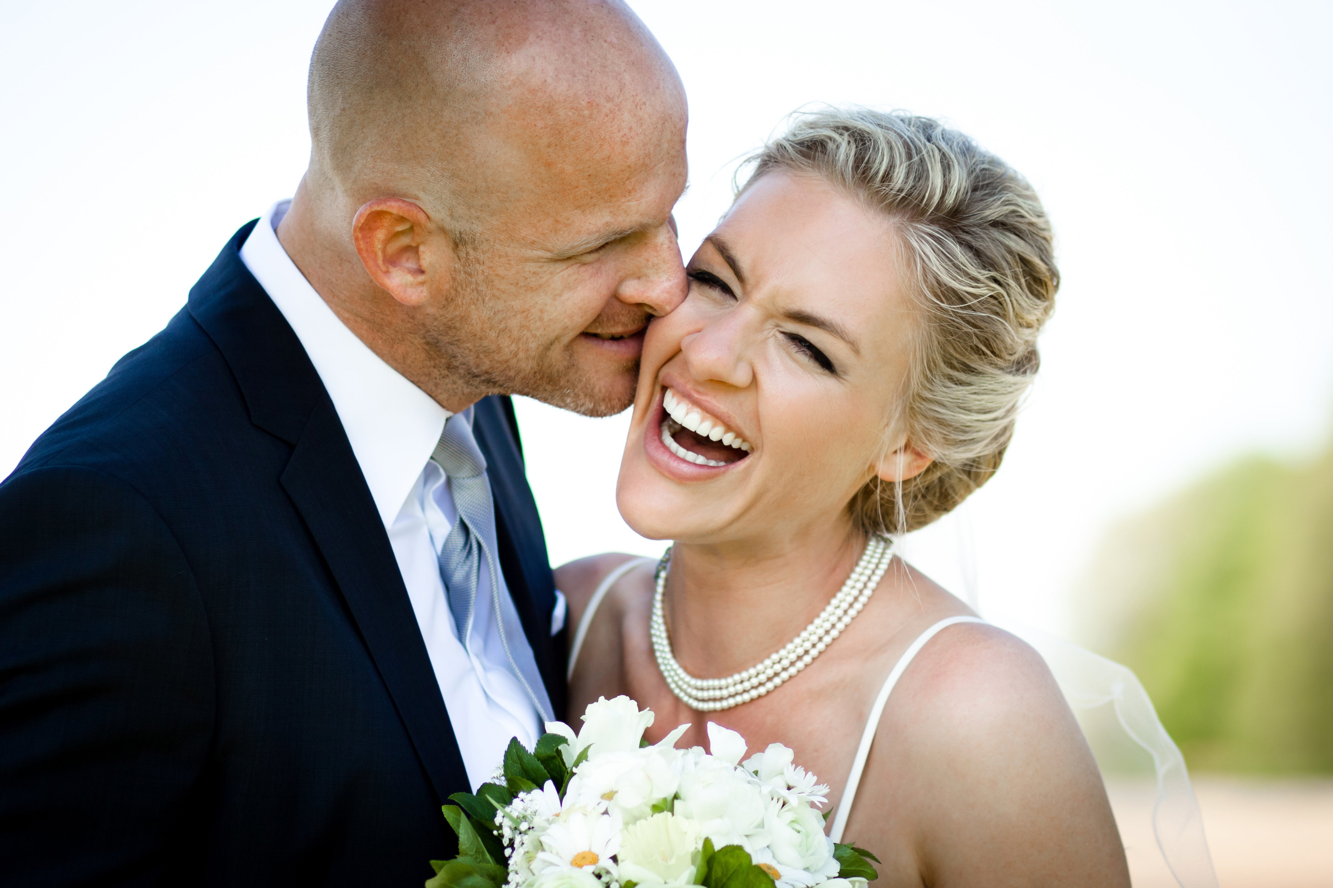 Candid wedding photo of groom sharing a secret with his bride