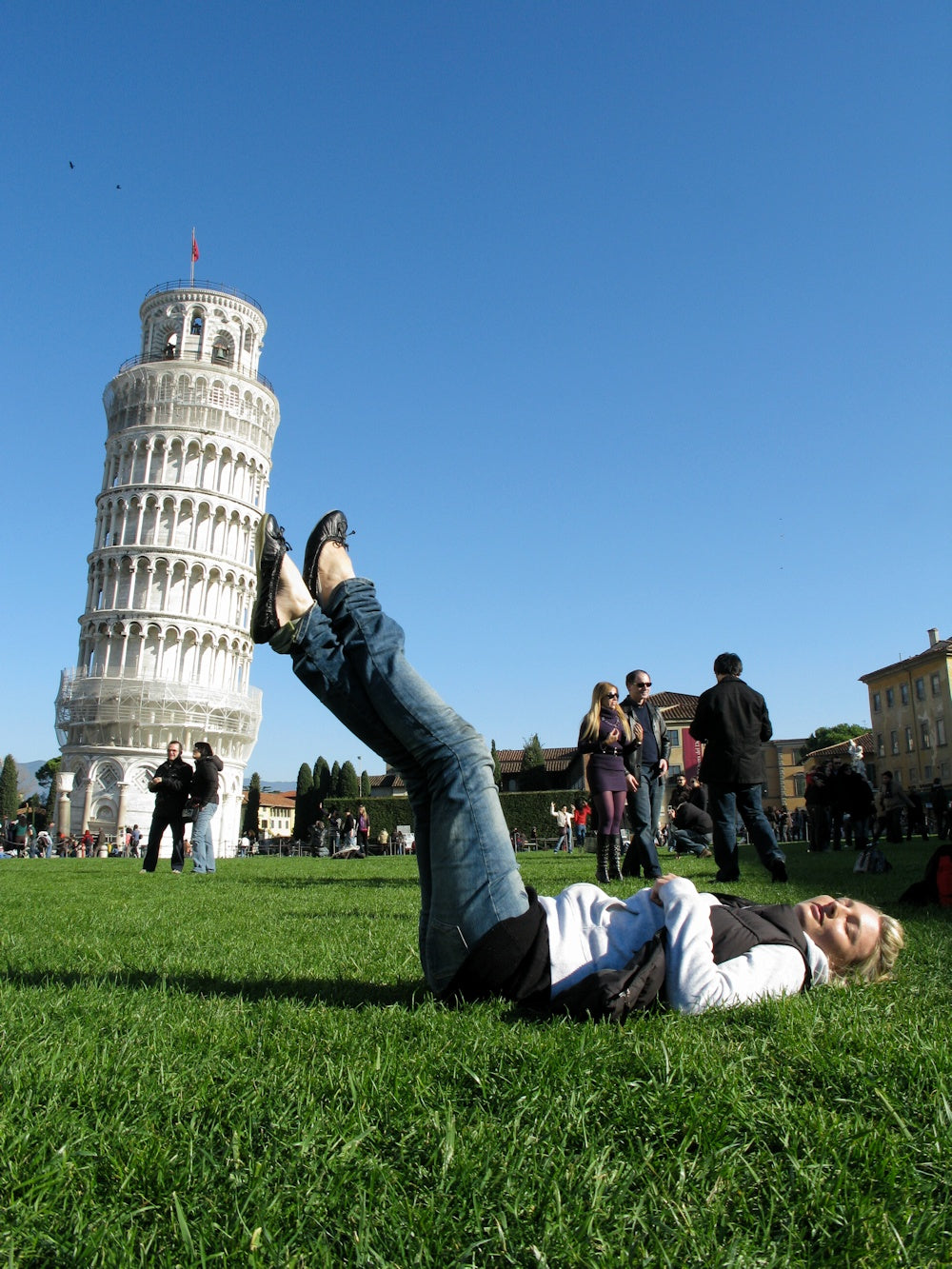 Forced perspective photo of a person holding up the Leaning Tower of Pisa with their legs