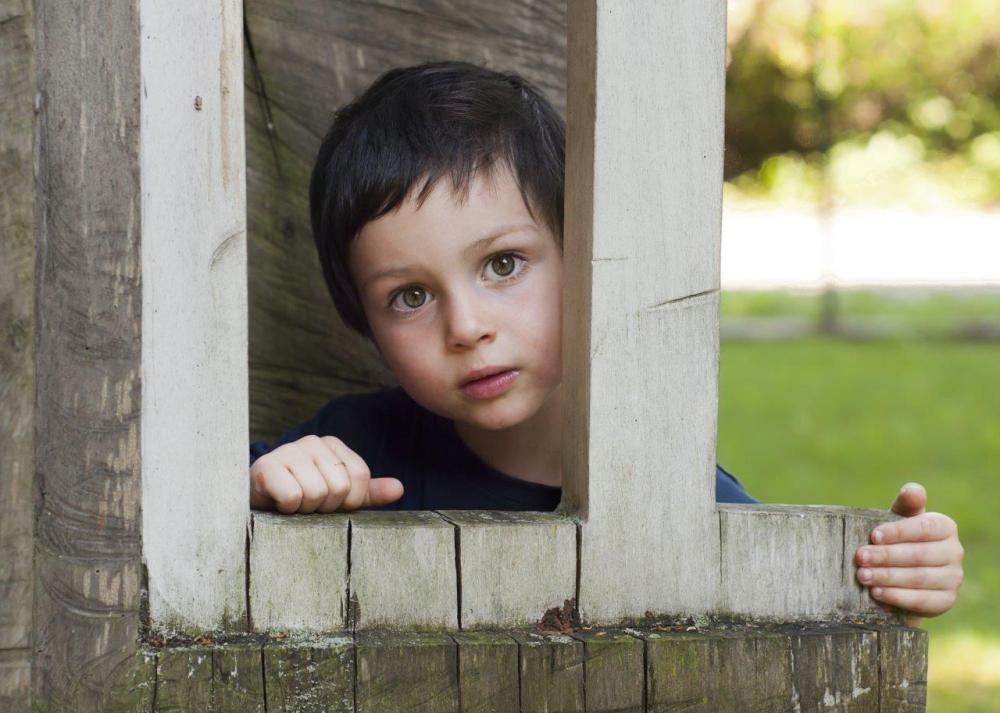 Little boy looking through a wood-framed window as an example of compositional framing