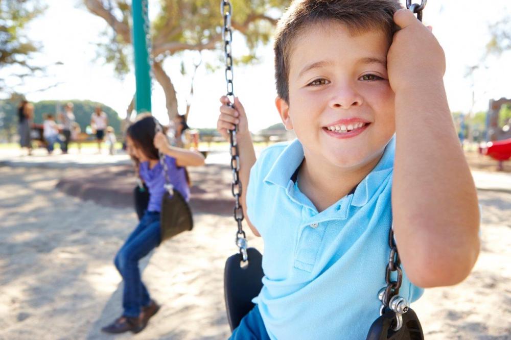 Boy smiling on a swing in the park - example of the rule of thirds in photography