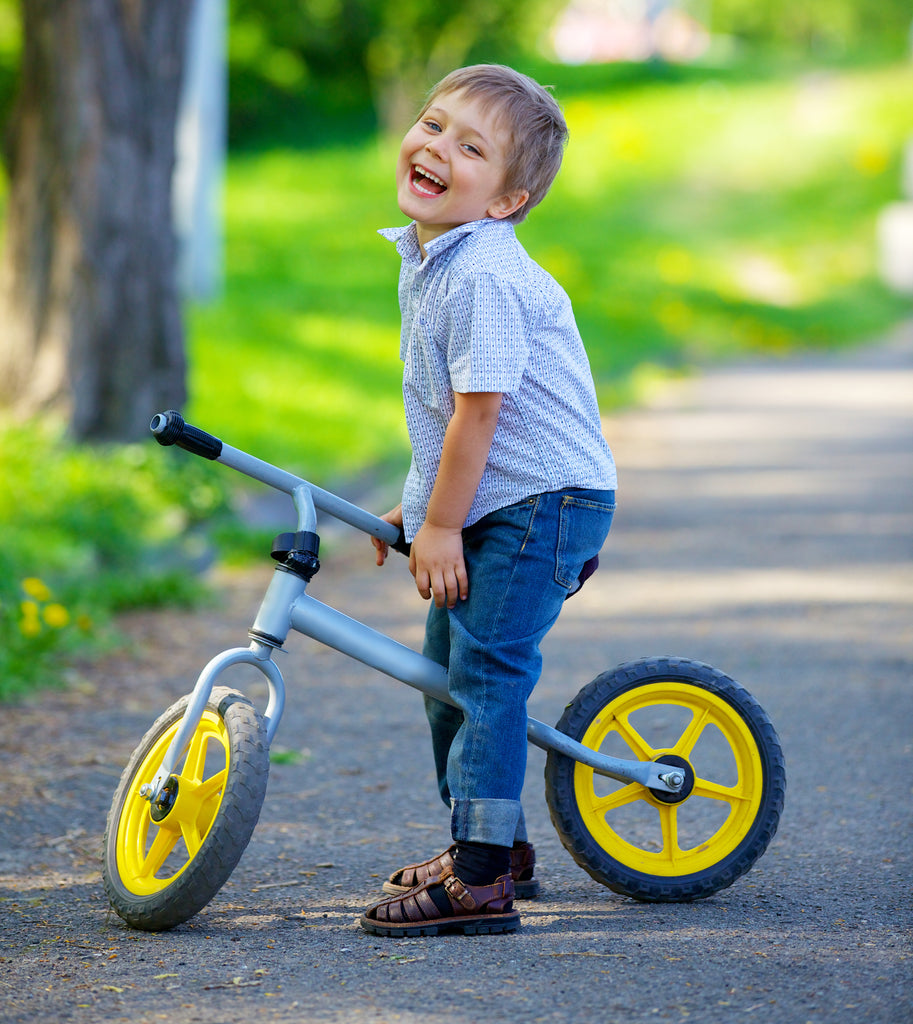 Happy little boy on a two-wheel bicycle with shallow depth of field
