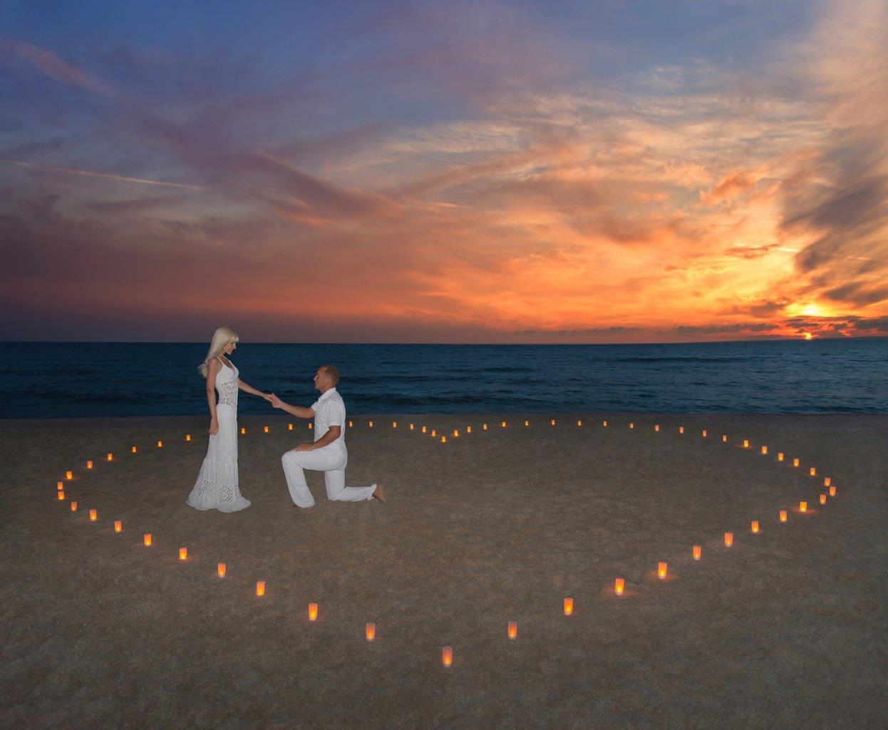 Man proposing to woman at sunset with candles arranged in the shape of a heart