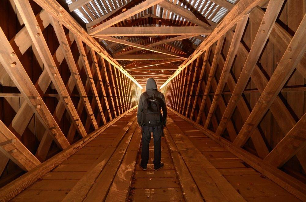 Person standing in wooden tunnel - example of converging leading lines in photography