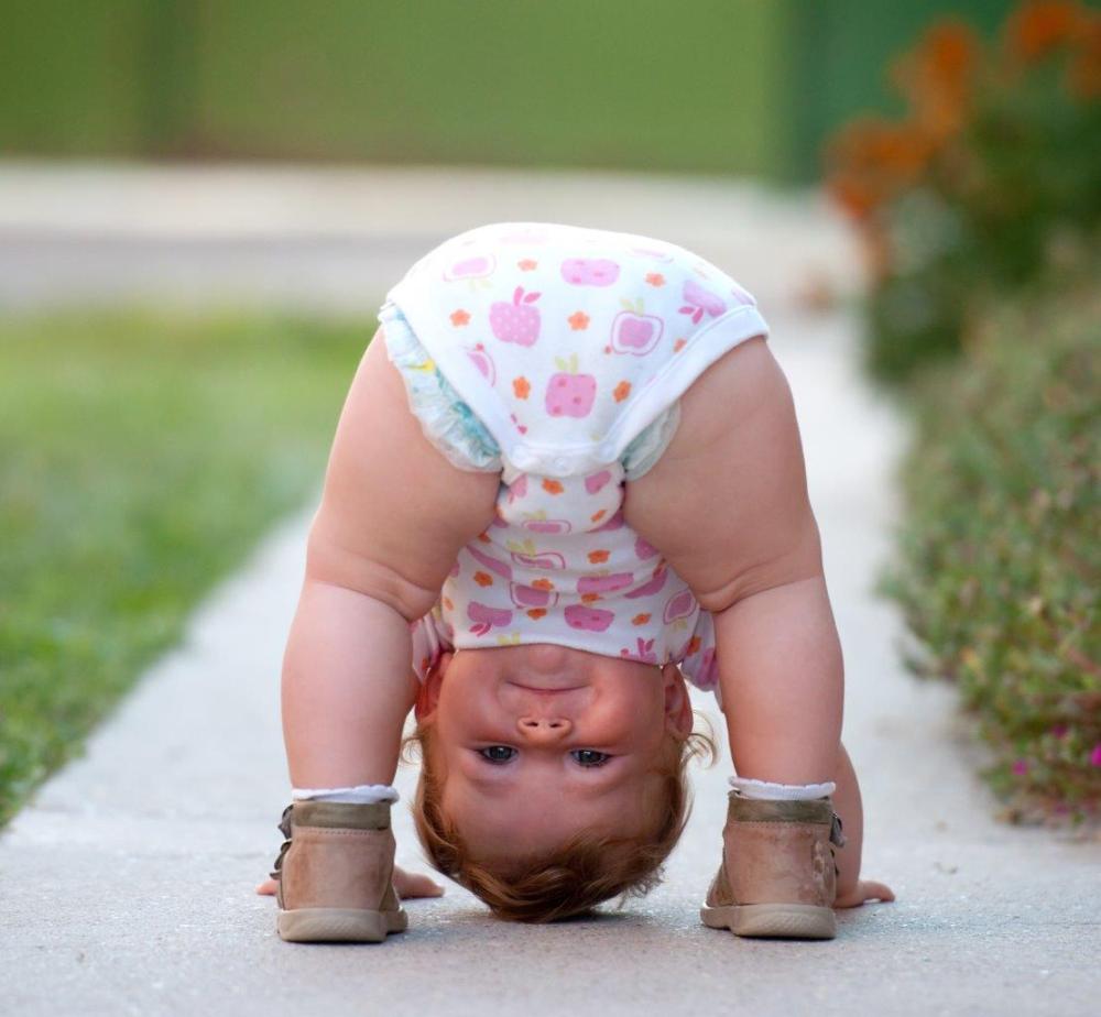 Little girl trying to stand on her head, peering through her legs