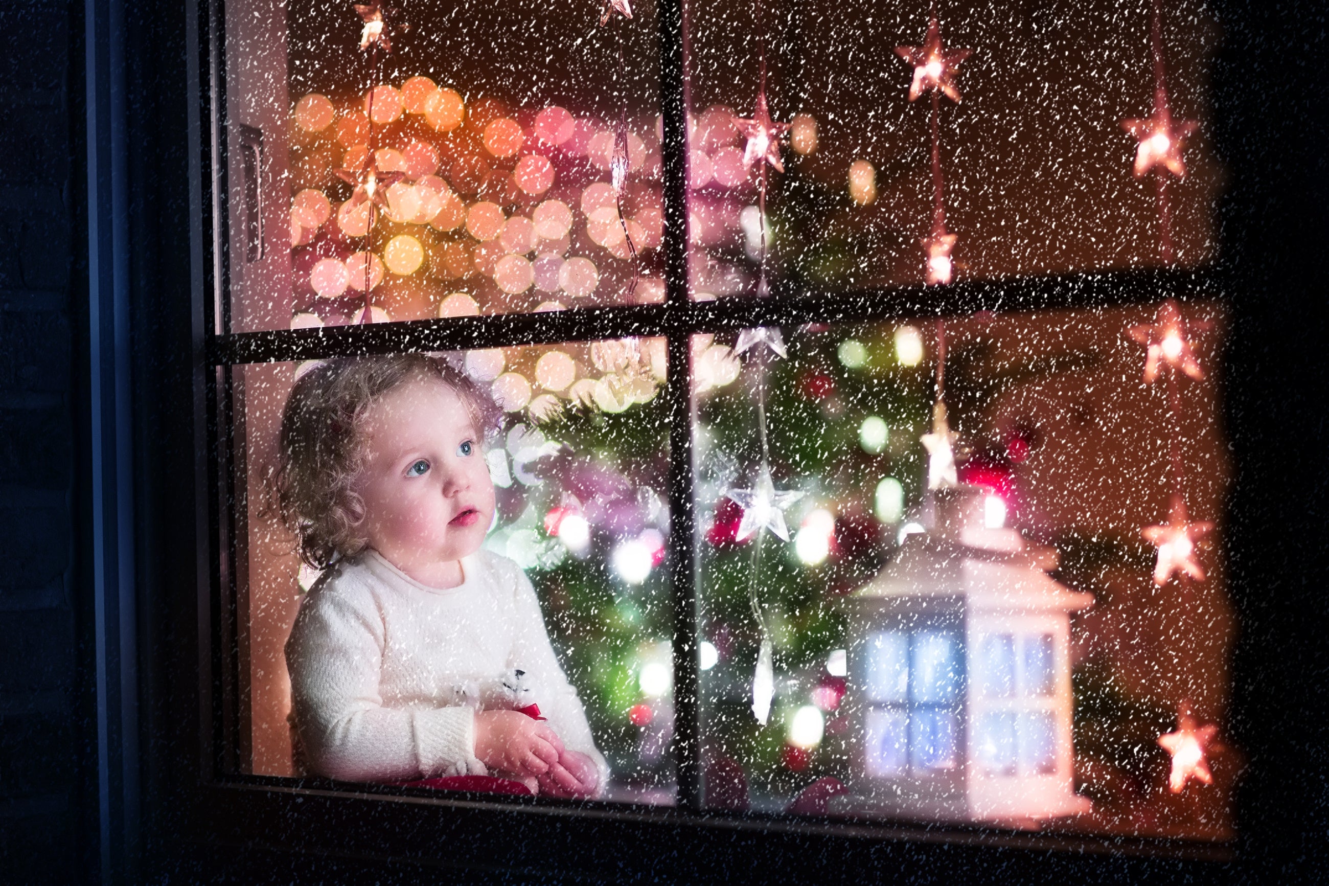 Young child looking out the window at snow on Christmas Eve - example of holiday photography