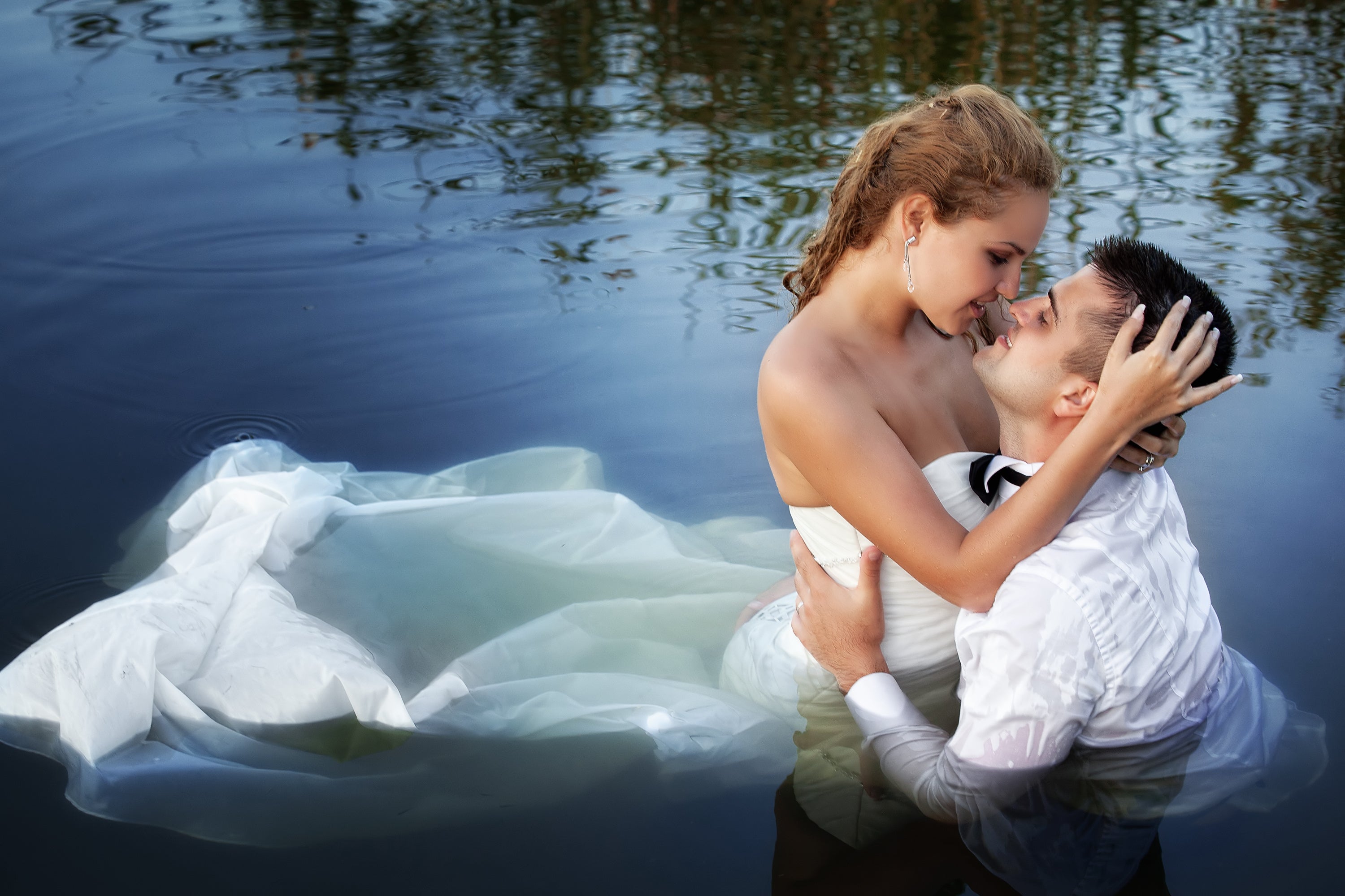 "Trash the Dress" photo of married bride and groom kissing in the water