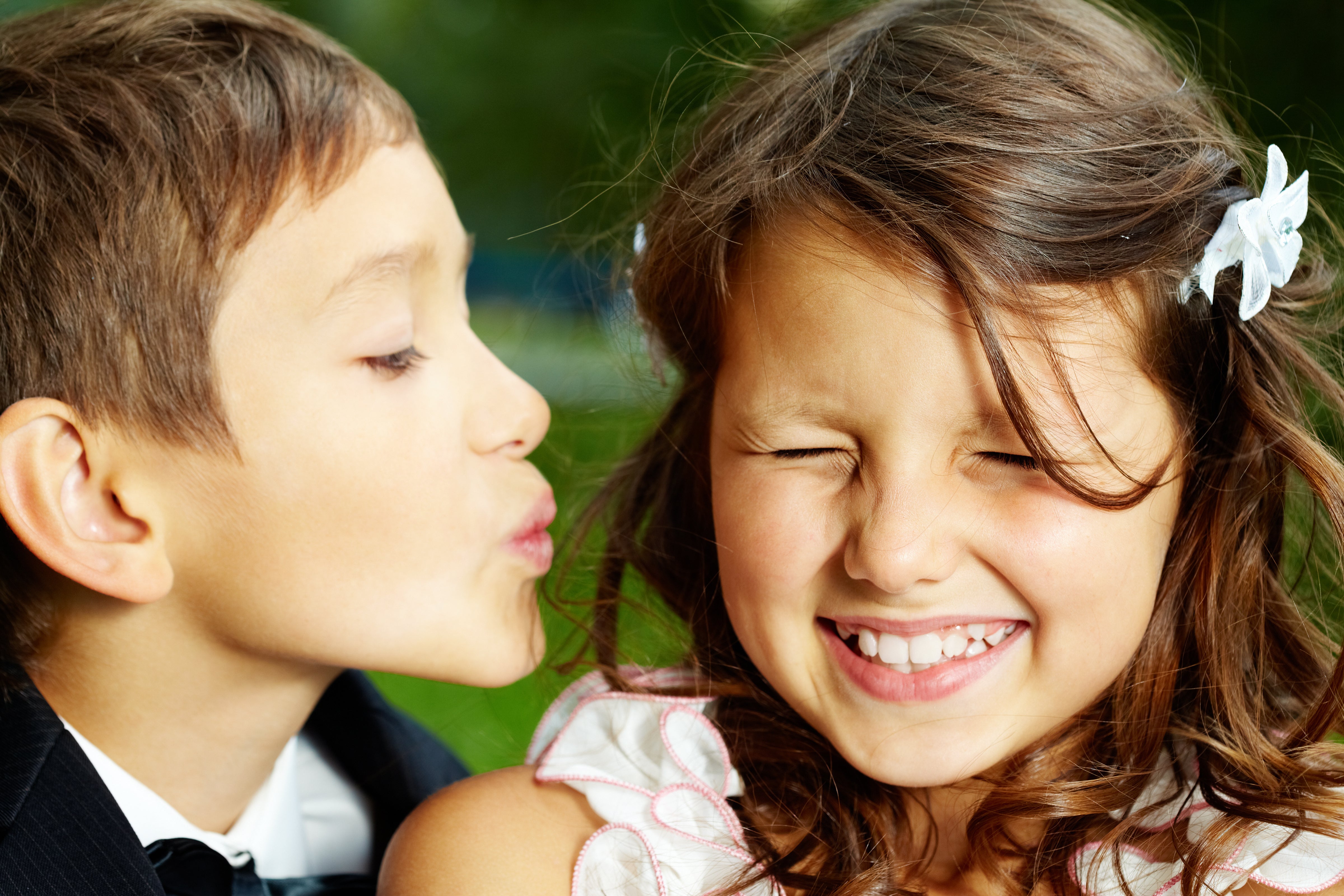 Wedding photo of a little boy trying to kiss a little girl