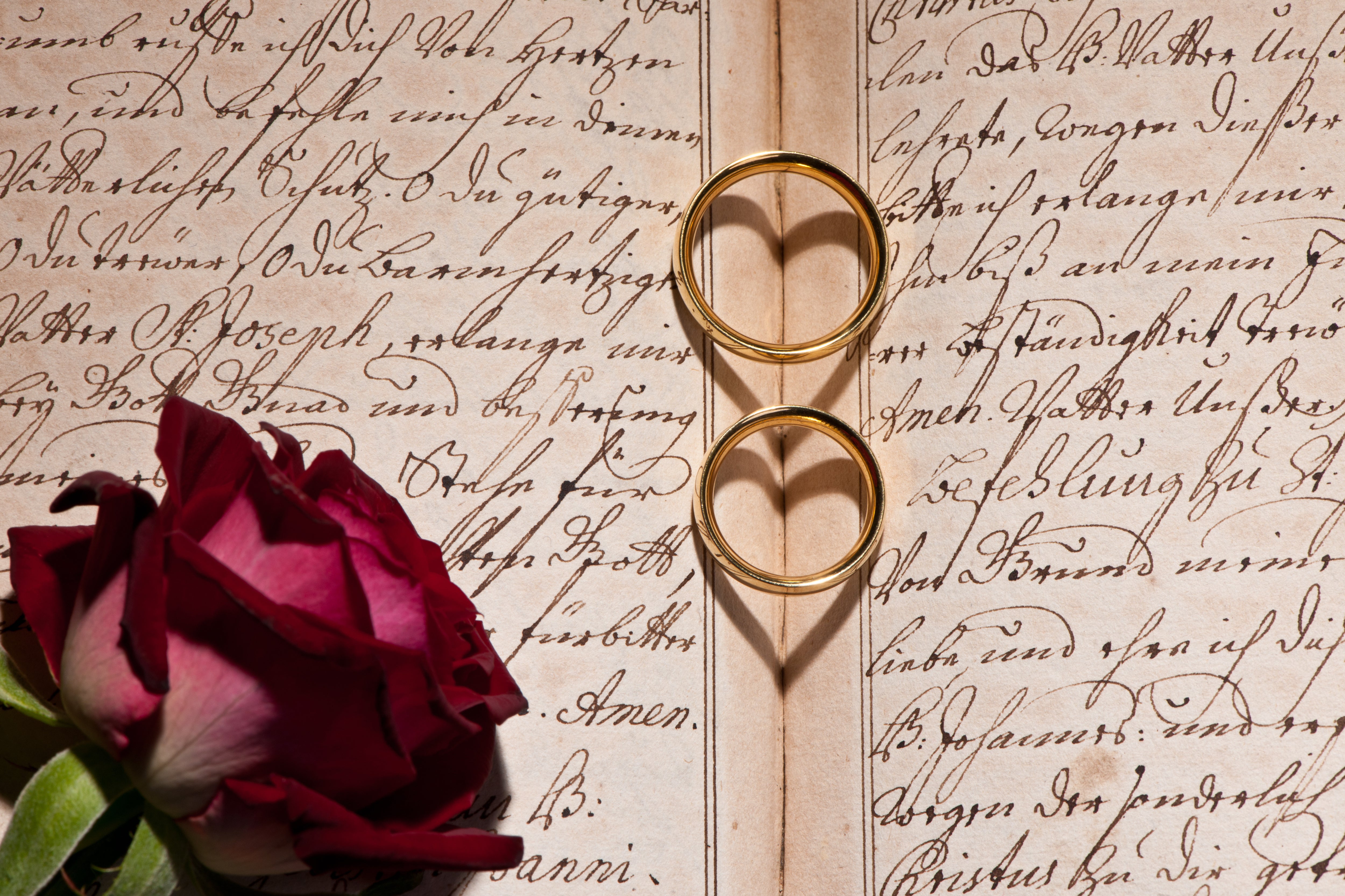 Wedding rings in a book with heart-shaped shadows