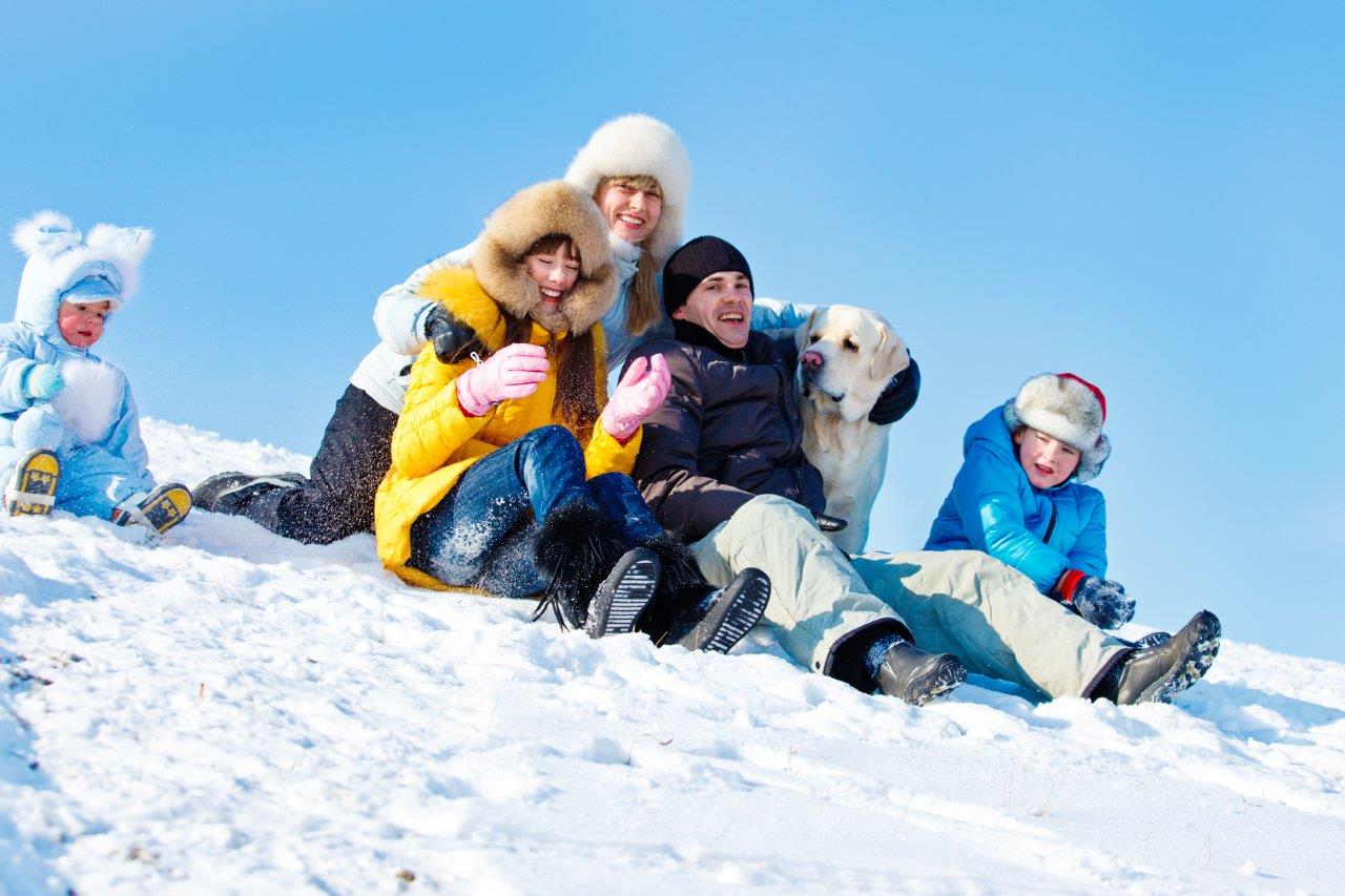 Winter holiday portrait of family and dog in the snow having fun