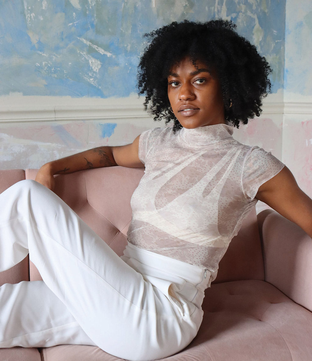 Woman sitting on the couch wearing the Nuudii Tee System in Creme wearing clothing