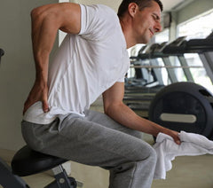 male athlete sits on a weight bench with a back injury