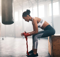 female boxer wraps her wrists before working out with a heavy bag