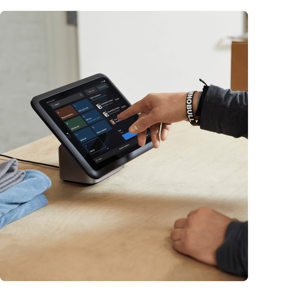 A person at a store check-out, using the Shopify point of sale tablet to complete their purchase.