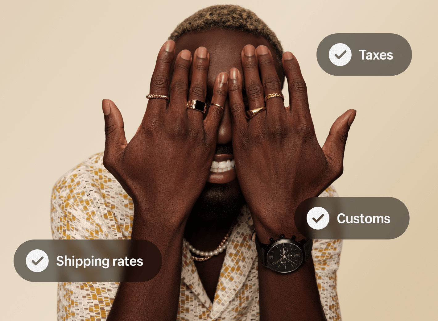 A merchant wearing a watch, multiple rings and two necklaces playfully hides their face behind their hands. A glimpse of their smile is visible behind their hands. Three superimposed graphics show the text Shipping rates, Taxes, and Customs with checkmarks next to them.
