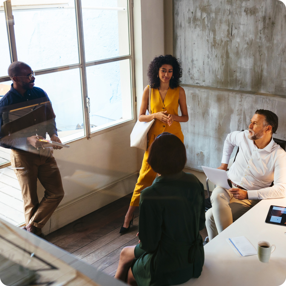 A diverse team of four business people holding a casual meeting in a shared space at the office.