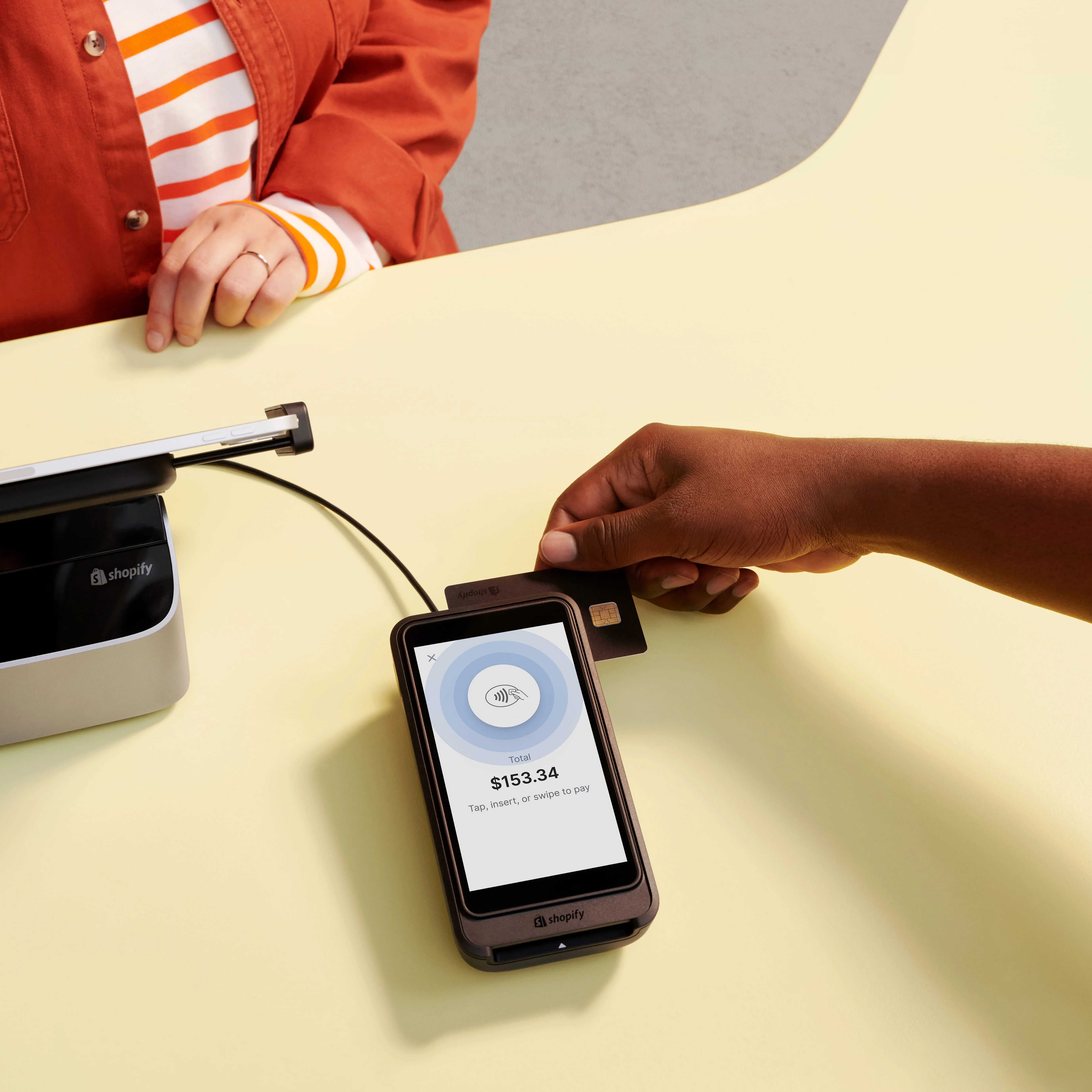 A POS tablet sits on a retail counter running Shopify POS on its display.