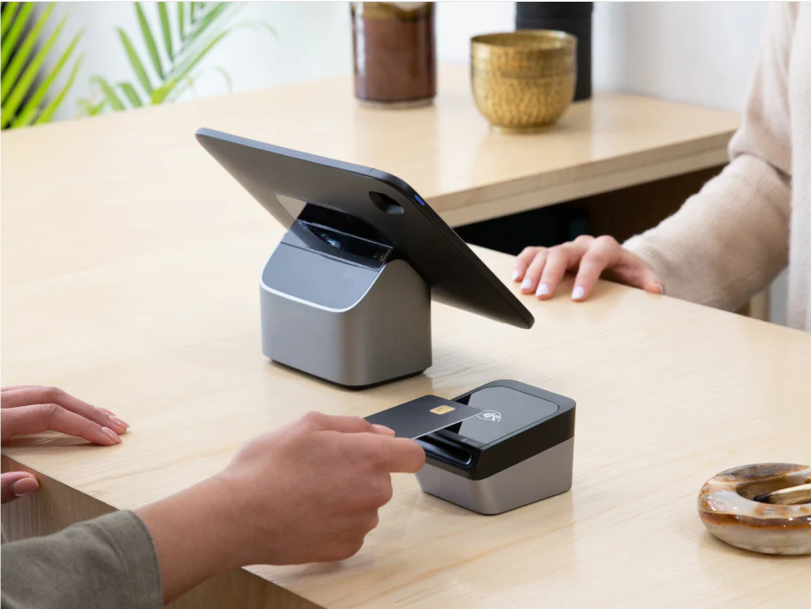 Customer tapping their card on the Tap & Chip Card Reader on a sales counter.