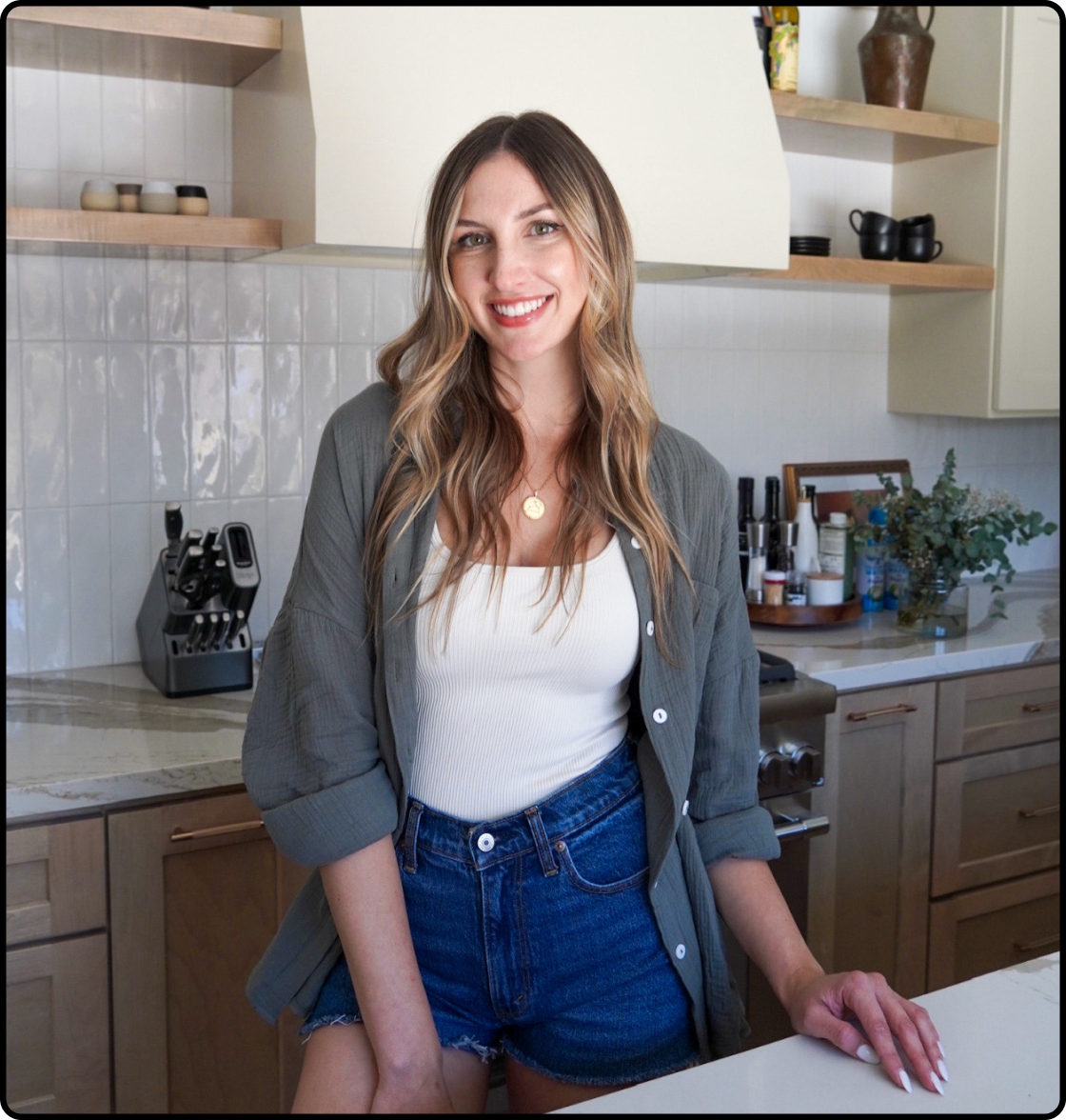 Hannah Kling, owner of Lovely Delites, smiling as she stands in kitchen with a hand resting on a white countertop.