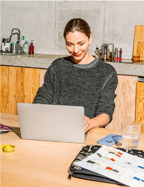 Photo d’un employé qui sourit derrière le comptoir de sa boutique et vend un sac à main à un client