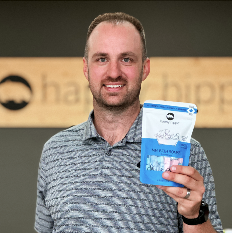 Adam Biel, CEO of Happy Hippo, holding a blue and white package of colorful Happy Hippo Mini Bath Bombs