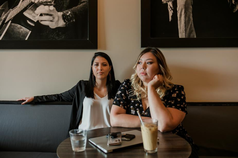 Two indigenous women sitting with a computer in a cafe