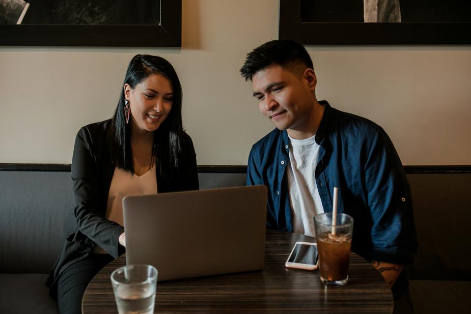 Indigenous woman and man looking at a computer while sitting in a cafe